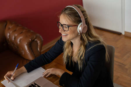 Young woman working at home with laptop and papers on desk and headphones. Home office concept. Gray notebook for working. high quality photoの写真素材