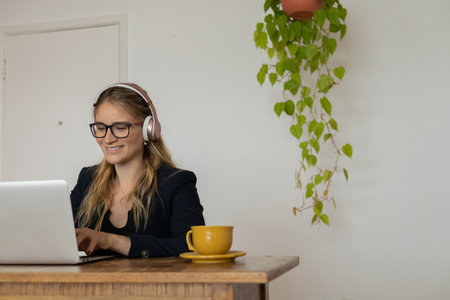 Young woman working at home with laptop and papers on desk and headphones. Home office concept. Gray notebook for working. high quality photoの写真素材