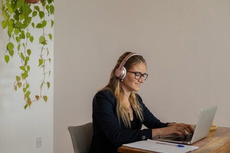 Young woman working at home with laptop and papers on desk and headphones. Home office concept. Gray notebook for working. high quality photoの写真素材