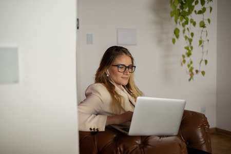 Young woman working at home with laptop and papers on desk and headphones. Home office concept. Gray notebook for working. high quality photoの写真素材
