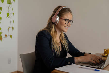 Young woman working at home with laptop and papers on desk and headphones. Home office concept. Gray notebook for working. high quality photoの写真素材