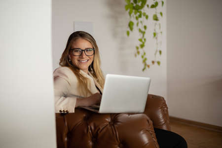 Young woman working at home with laptop and papers on desk and headphones. Home office concept. Gray notebook for working. high quality photoの写真素材