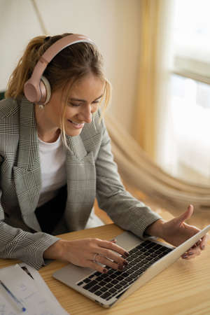 Young woman working at home with laptop and papers on desk and headphones. Home office concept. Gray notebook for working. high quality photoの写真素材