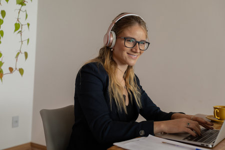 Young woman working at home with laptop and papers on desk and headphones. Home office concept. Gray notebook for working. high quality photoの写真素材
