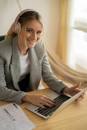 Young woman working at home with laptop and papers on desk and headphones. Home office concept. Gray notebook for working. high quality photoの写真素材