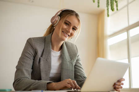 Young woman working at home with laptop and papers on desk in her bedroom. Home office concept. Gray notebook for working. high quality photoの写真素材
