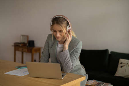 Young woman working at home with laptop and papers on desk in her bedroom. Home office concept. Gray notebook for working. high quality photoの写真素材