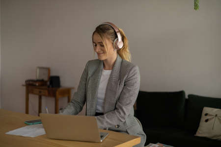 Young woman working at home with laptop and papers on desk in her bedroom. Home office concept. Gray notebook for working. high quality photoの写真素材