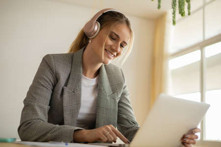 Young woman working at home with laptop and papers on desk in her bedroom. Home office concept. Gray notebook for working. high quality photoの写真素材
