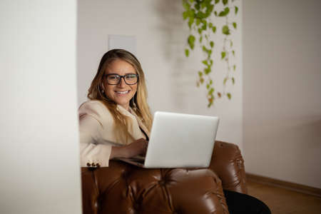 Young woman working at home with laptop and papers on desk in her bedroom. Home office concept. Gray notebook for working. high quality photoの写真素材