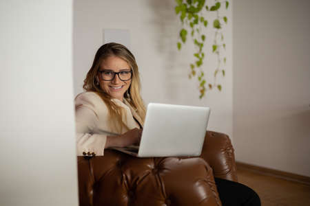 Young woman working at home with laptop and papers on desk in her bedroom. Home office concept. Gray notebook for working. high quality photoの写真素材