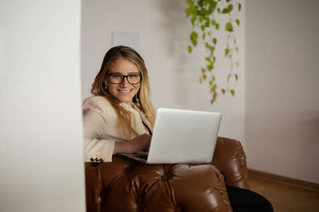 Young woman working at home with laptop and papers on desk in her bedroom. Home office concept. Gray notebook for working. high quality photoの写真素材