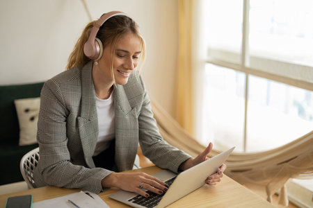 Young woman working at home with laptop and papers on desk in her bedroom. Home office concept. Gray notebook for working. high quality photoの写真素材