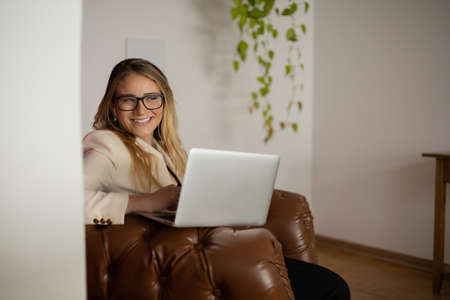 Young woman working at home with laptop and papers on desk in her bedroom. Home office concept. Gray notebook for working. high quality photoの写真素材