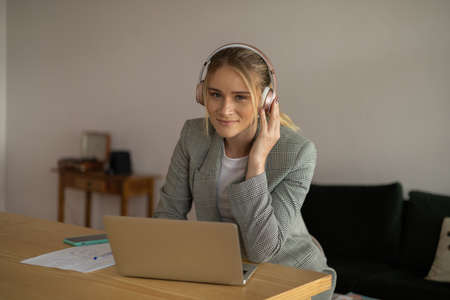Young woman working at home with laptop and papers on desk in her bedroom. Home office concept. Gray notebook for working. high quality photoの写真素材