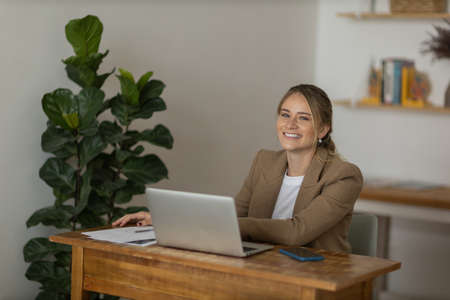 Young woman working at home with laptop and papers on desk in her bedroom. Home office concept. Gray notebook for working. high quality photoの写真素材