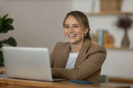 Young woman working at home in her kitchen with laptop and papers on kitchen wooden desk. Home office concept. Gray notebook for working. Home office concept. high quality photoの写真素材