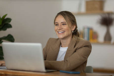Young woman working at home in her kitchen with laptop and papers on kitchen wooden desk. Home office concept. Gray notebook for working. Home office concept. high quality photoの写真素材
