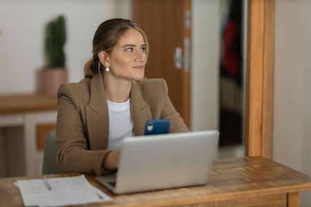 Young woman working at home in her kitchen with laptop and papers on kitchen wooden desk. Home office concept. Gray notebook for working. Home office concept. high quality photoの写真素材