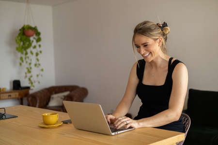 Young woman working at home from her living room couch with laptop on her lap. Home office concept. Gray notebook for working. Home office concept. high quality photoの写真素材