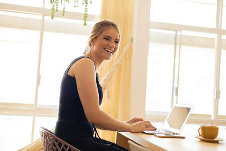 Young woman working at home from her living room couch with laptop on her lap. Home office concept. Gray notebook for working. Home office concept. high quality photoの写真素材