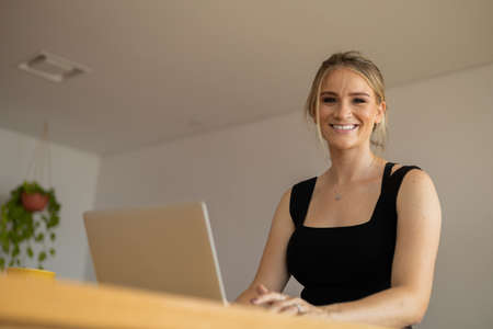 Young woman working at home from her living room couch with laptop on her lap. Home office concept. Gray notebook for working. Home office concept. high quality photoの写真素材