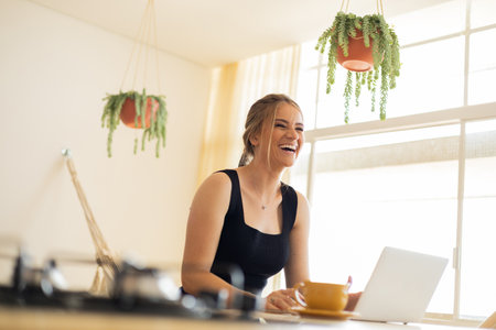 Young woman working at home from her living room couch with laptop on her lap. Home office concept. Gray notebook for working. Home office concept. high quality photoの写真素材
