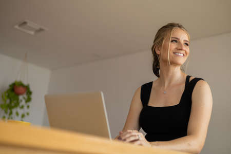 Young woman working at home from her living room couch with laptop on her lap. Home office concept. Gray notebook for working. Home office concept. high quality photoの写真素材