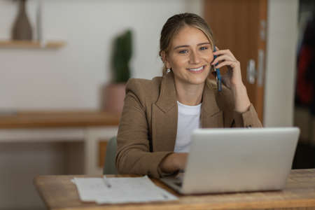 Young woman working at home from her living room couch with laptop on her lap. Home office concept. Gray notebook for working. Home office concept. high quality photoの写真素材