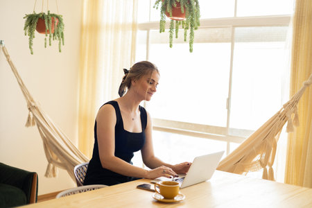 Young woman working at home from her living room couch with laptop on her lap. Home office concept. Gray notebook for working. Home office concept. high quality photoの写真素材