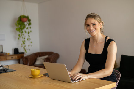 Young woman working at home from her living room couch with laptop on her lap. Home office concept. Gray notebook for working. Home office concept. high quality photoの写真素材