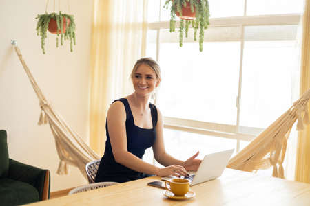 Young woman working at home from her living room couch with laptop on her lap. Home office concept. Gray notebook for working. Home office concept. high quality photoの写真素材