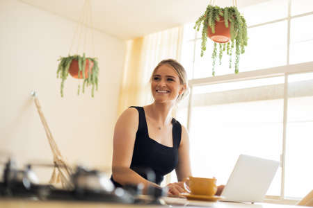 Young woman working at home from her living room couch with laptop on her lap. Home office concept. Gray notebook for working. Home office concept. high quality photoの写真素材