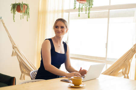 Young woman working at home from her living room couch with laptop on her lap. Home office concept. Gray notebook for working. Home office concept. high quality photoの写真素材