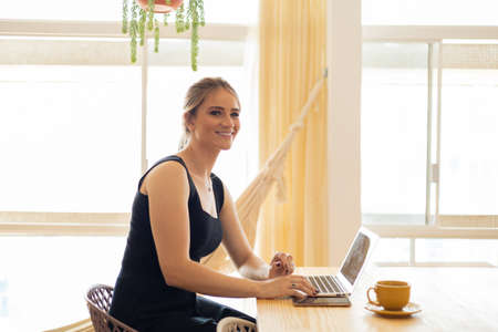Young woman working at home from her living room couch with laptop on her lap. Home office concept. Gray notebook for working. Home office concept. high quality photoの写真素材