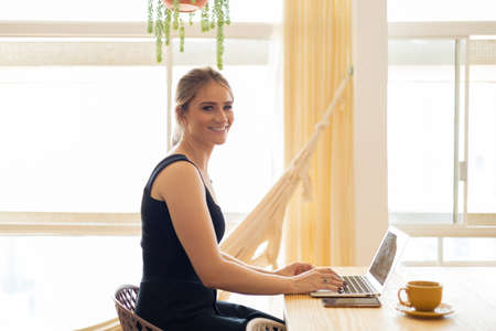 Young woman working at home from her living room couch with laptop on her lap. Home office concept. Gray notebook for working. Home office concept. high quality photoの写真素材