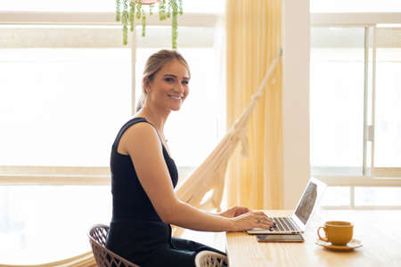Young woman working at home from her living room couch with laptop on her lap. Home office concept. Gray notebook for working. Home office concept. high quality photoの写真素材