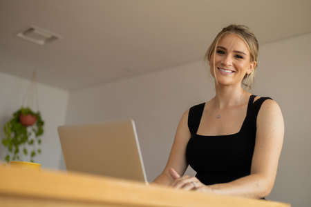 Young woman working at home in his kitchen with laptop and papers on kitchen wooden desk. Home office concept. Gray notebook for working. Home office concept. high quality photoの写真素材