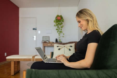 Young woman working at home in his kitchen with laptop and papers on kitchen wooden desk. Home office concept. Gray notebook for working. Home office concept. high quality photoの写真素材