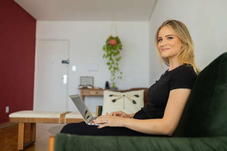 Young woman working at home in his kitchen with laptop and papers on kitchen wooden desk. Home office concept. Gray notebook for working. Home office concept. high quality photoの写真素材