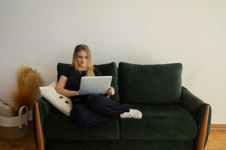 Young woman working at home in his kitchen with laptop and papers on kitchen wooden desk. Home office concept. Gray notebook for working. Home office concept. high quality photoの写真素材