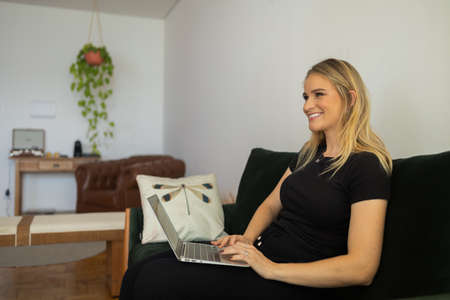 Young woman working at home in his kitchen with laptop and papers on kitchen wooden desk. Home office concept. Gray notebook for working. Home office concept. high quality photoの写真素材