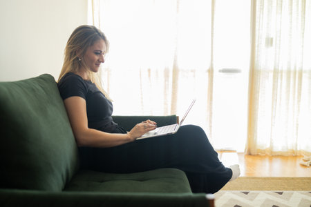 Young woman working at home in his kitchen with laptop and papers on kitchen wooden desk. Home office concept. Gray notebook for working. Home office concept. high quality photoの写真素材