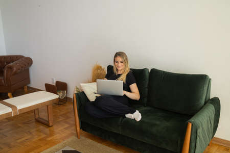 Young woman working at home in his kitchen with laptop and papers on kitchen wooden desk. Home office concept. Gray notebook for working. Home office concept. high quality photoの写真素材