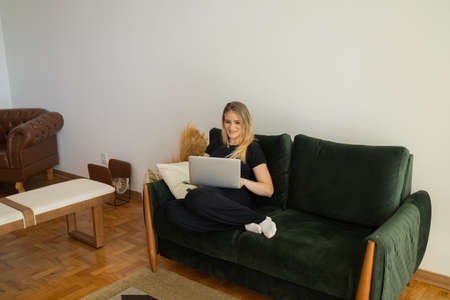 Young woman working at home from her bedroom with laptop on her bed. Woman lying down. Home office concept. Gray notebook for working. Cozy and comfortable. Home office concept. high quality photoの写真素材