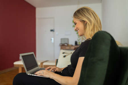 Young woman working at home from her bedroom with laptop on her bed. Woman lying down. Home office concept. Gray notebook for working. Cozy and comfortable. Home office concept. high quality photoの写真素材