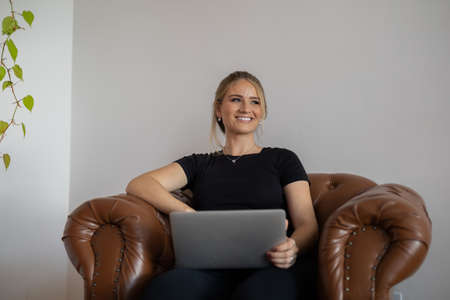 Young woman working at home from her bedroom with laptop on her bed. Woman lying down. Home office concept. Gray notebook for working. Cozy and comfortable. Home office concept. high quality photoの写真素材