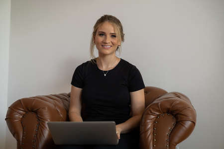 Young woman working at home from her bedroom with laptop on her bed. Woman lying down. Home office concept. Gray notebook for working. Cozy and comfortable. Home office concept. high quality photoの写真素材