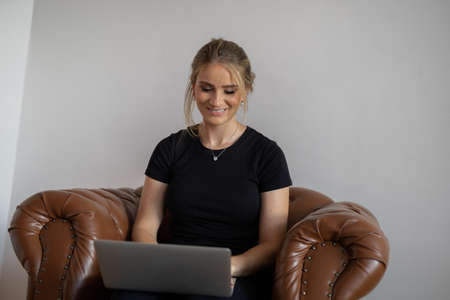 Young woman working at home from her bedroom with laptop on her bed. Woman lying down. Home office concept. Gray notebook for working. Cozy and comfortable. Home office concept. high quality photoの写真素材