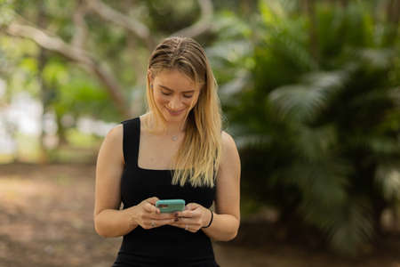 Young woman using a smartphone at night time with city view landscape in the background. High quality photo. photo. Mobile phone, technology, urban concept.の写真素材